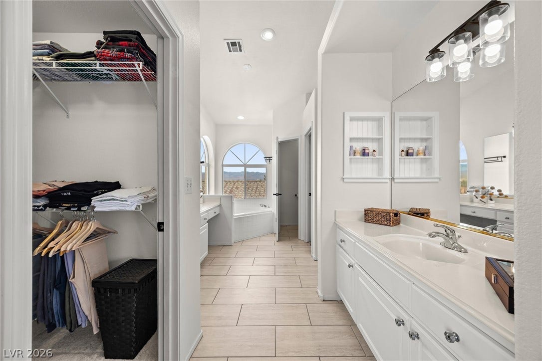 1421 Dragon Rock Drive, Henderson, NV 89052 Sleek tile flooring guides the eye through this bright bathroom with integrated closet storage.