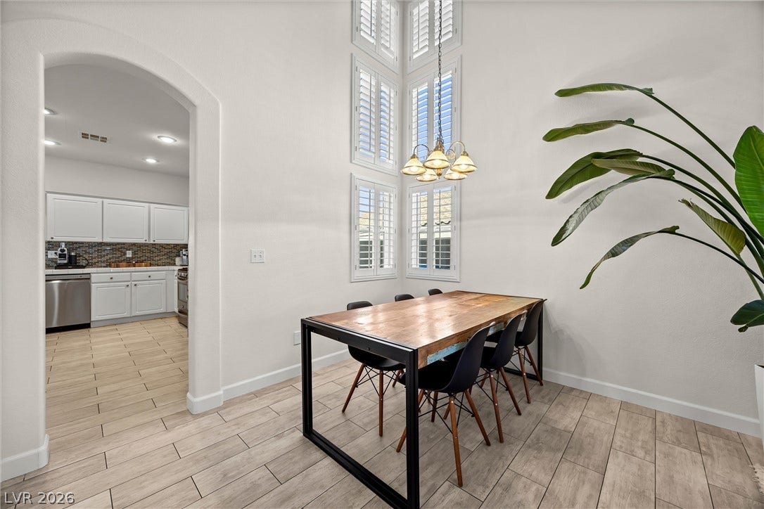 1421 Dragon Rock Drive, Henderson, NV 89052 Soaring ceilings and tall shuttered windows illuminate this inviting dining space with wood-look tile floors.