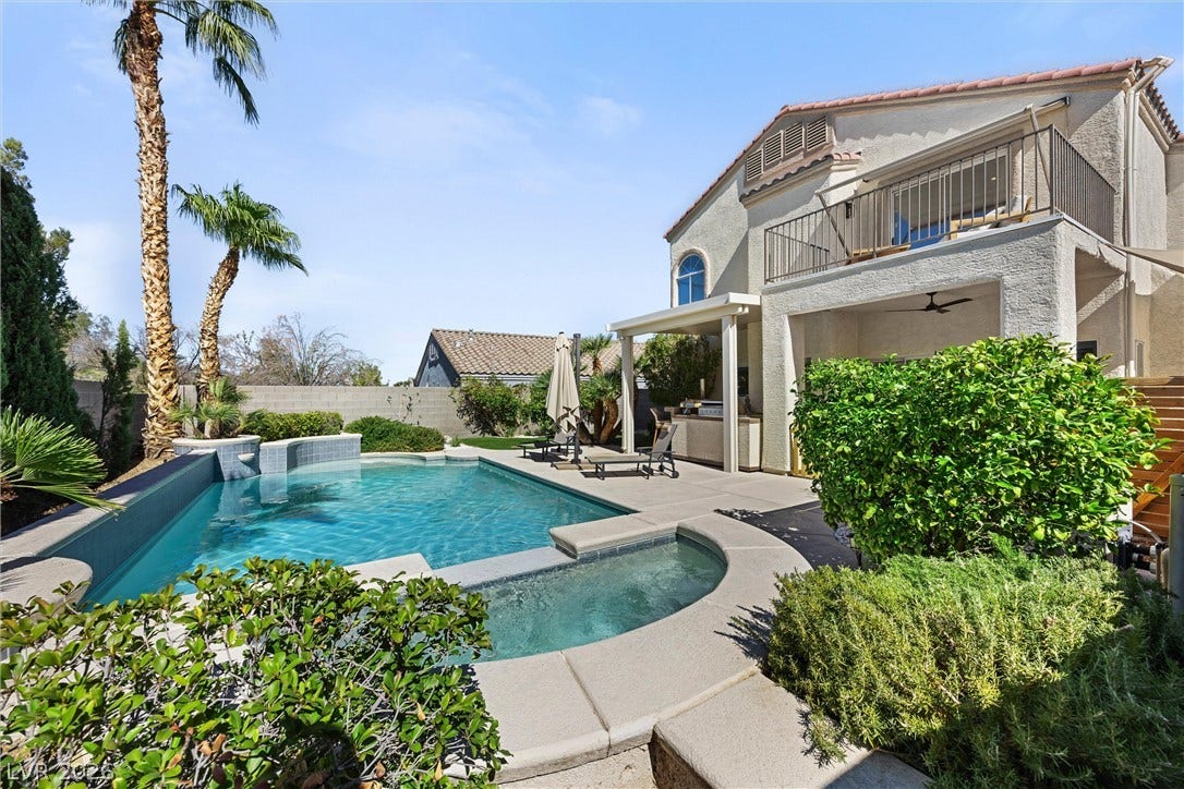 1421 Dragon Rock Drive, Henderson, NV 89052 An inviting backyard oasis features a shimmering pool and spa alongside mature palms and landscaping.