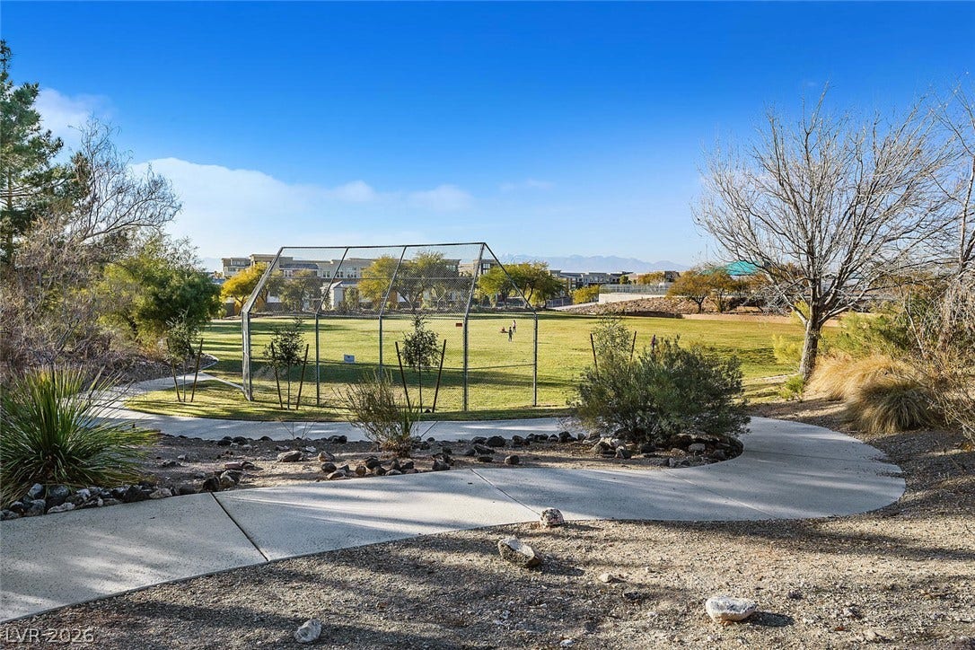 1421 Dragon Rock Drive, Henderson, NV 89052 Winding concrete pathways lead to a grassy neighborhood park featuring sports fields and mountain backdrops.