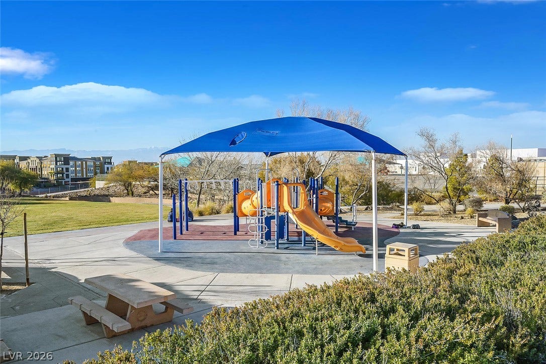 1421 Dragon Rock Drive, Henderson, NV 89052 An inviting playground structure under a blue canopy sits adjacent to a grassy park area.