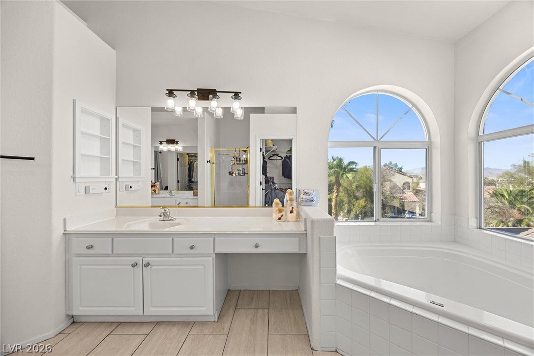 1421 Dragon Rock Drive, Henderson, NV 89052 Arched windows frame tranquil views beside a deep soaking tub in this bright bathroom.