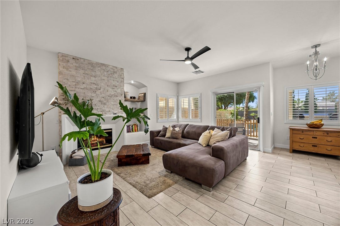 1421 Dragon Rock Drive, Henderson, NV 89052 A stone fireplace accents this open living space featuring light tile flooring and glass sliding doors.