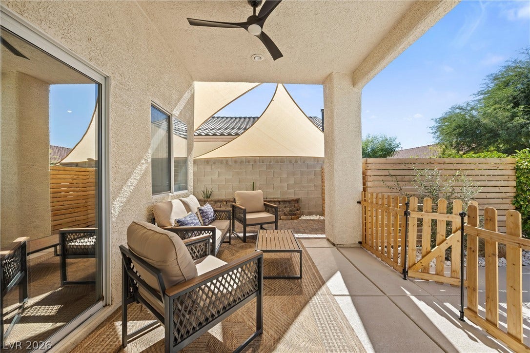 1421 Dragon Rock Drive, Henderson, NV 89052 A covered patio with concrete flooring opens to a fenced backyard under clear blue skies.