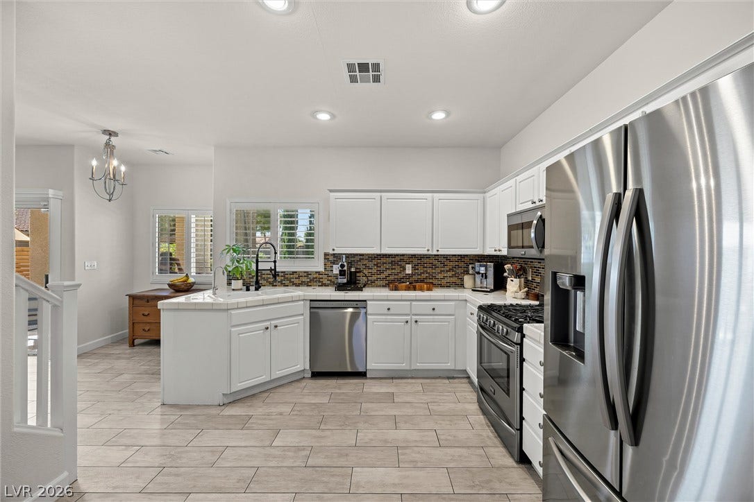 1421 Dragon Rock Drive, Henderson, NV 89052 White cabinetry paired with stainless steel appliances anchors this modern culinary space.