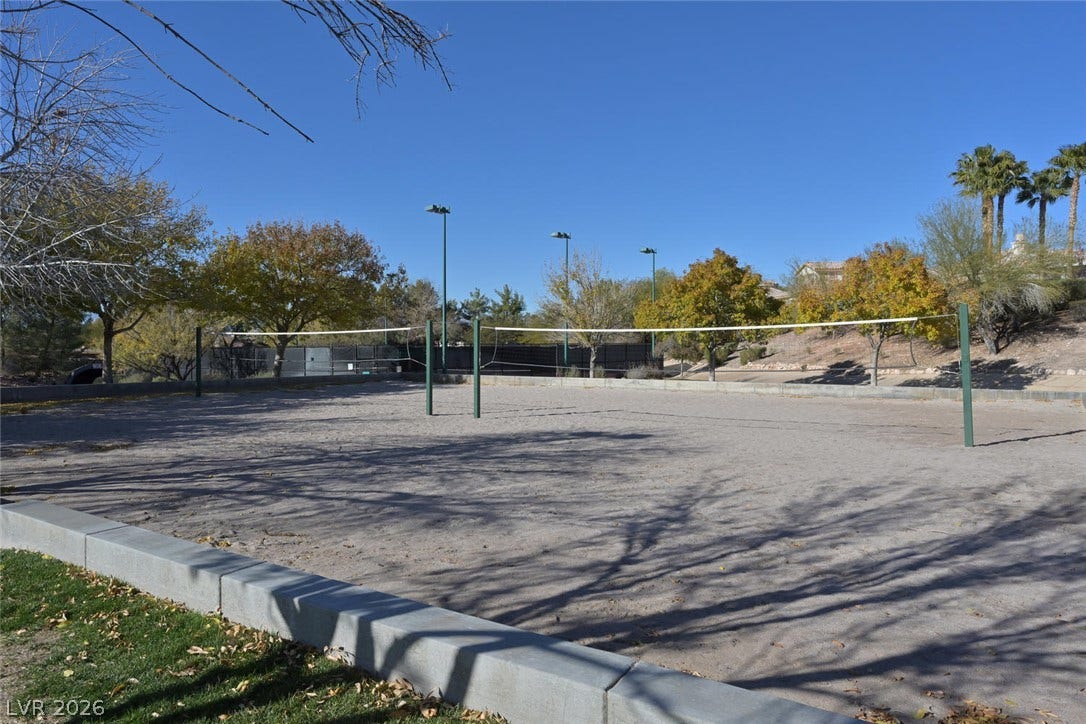 1421 Dragon Rock Drive, Henderson, NV 89052 A spacious sand volleyball court sits under clear blue skies surrounded by mature trees.