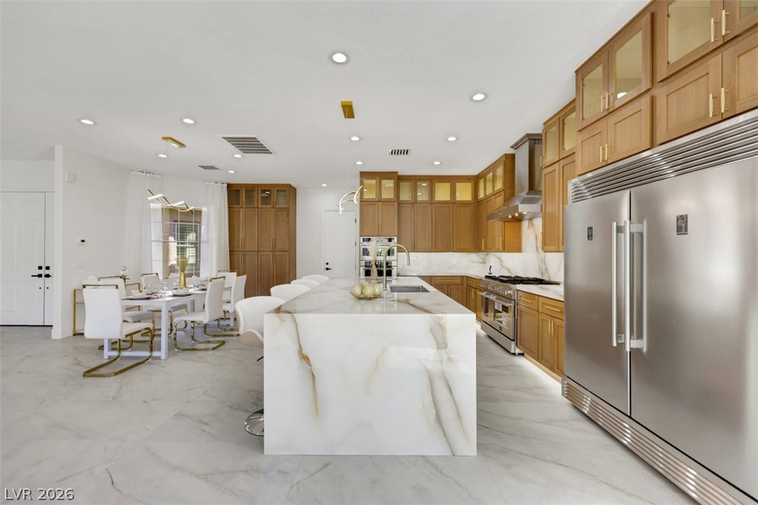 5015 Rivedro Street, Las Vegas, NV 89135 Rich wood cabinetry contrasts beautifully with a massive stone waterfall island in this open kitchen.