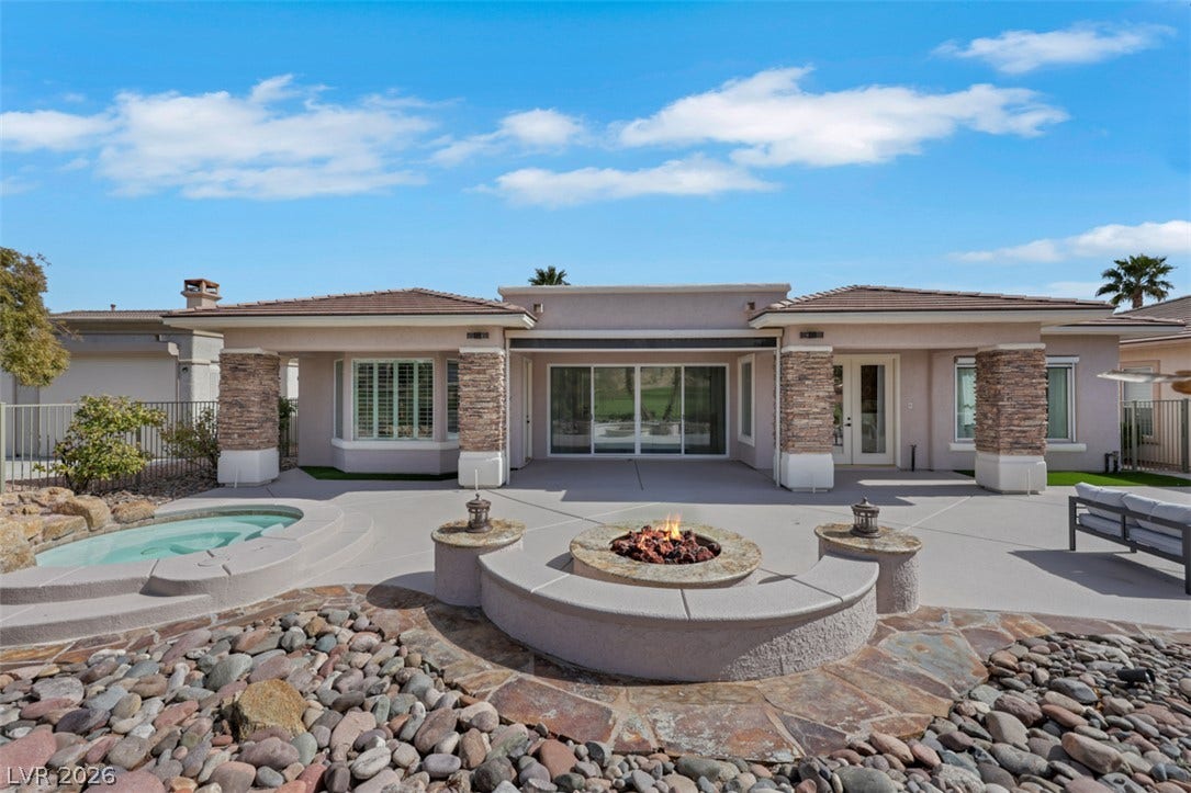 5015 Rivedro Street, Las Vegas, NV 89135 An inviting backyard patio features a circular fire pit alongside stone columns and glass sliders.