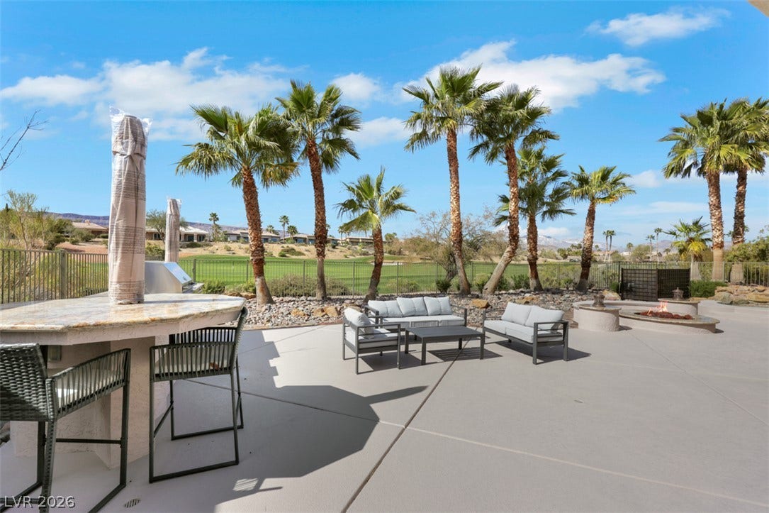 5015 Rivedro Street, Las Vegas, NV 89135 A spacious stone patio overlooks a manicured golf course framed by mature palm trees.