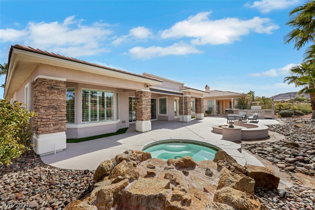 5015 Rivedro Street, Las Vegas, NV 89135 Stone pillars frame the covered patio overlooking a built-in spa and rock-lined fire pit area.