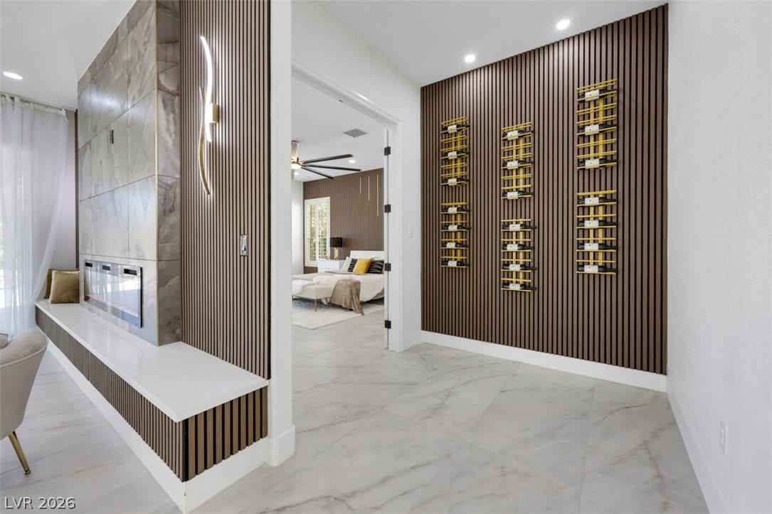 5015 Rivedro Street, Las Vegas, NV 89135 Elegant wood-paneled accents and polished tile flooring frame a dual-sided modern fireplace.