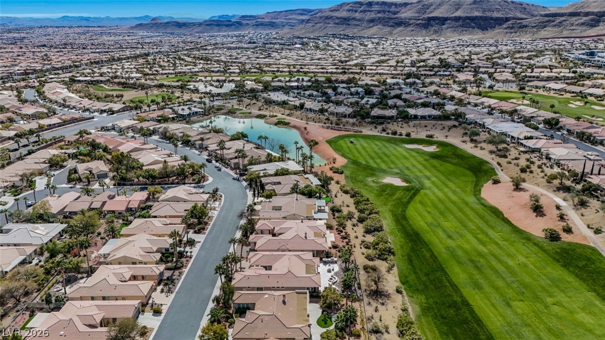 5015 Rivedro Street, Las Vegas, NV 89135 An aerial perspective showcases a suburban community bordering a golf course with desert mountain backdrops.