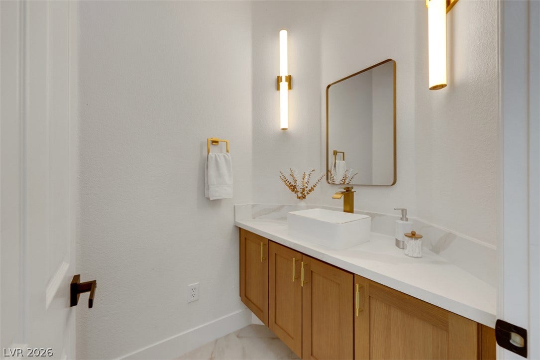 5015 Rivedro Street, Las Vegas, NV 89135 Gold fixtures accent a sleek floating-look vanity with crisp stone countertops.