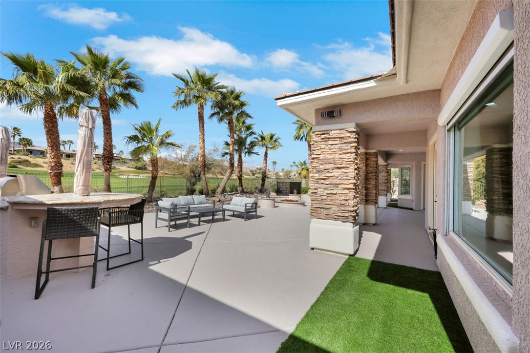 5015 Rivedro Street, Las Vegas, NV 89135 An expansive concrete patio features stone columns, an outdoor bar, and serene golf course views.