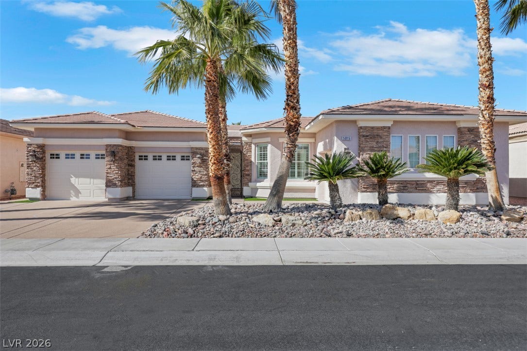 5015 Rivedro Street, Las Vegas, NV 89135 Palm trees and stone accents frame this desert-style home featuring a multi-car garage.