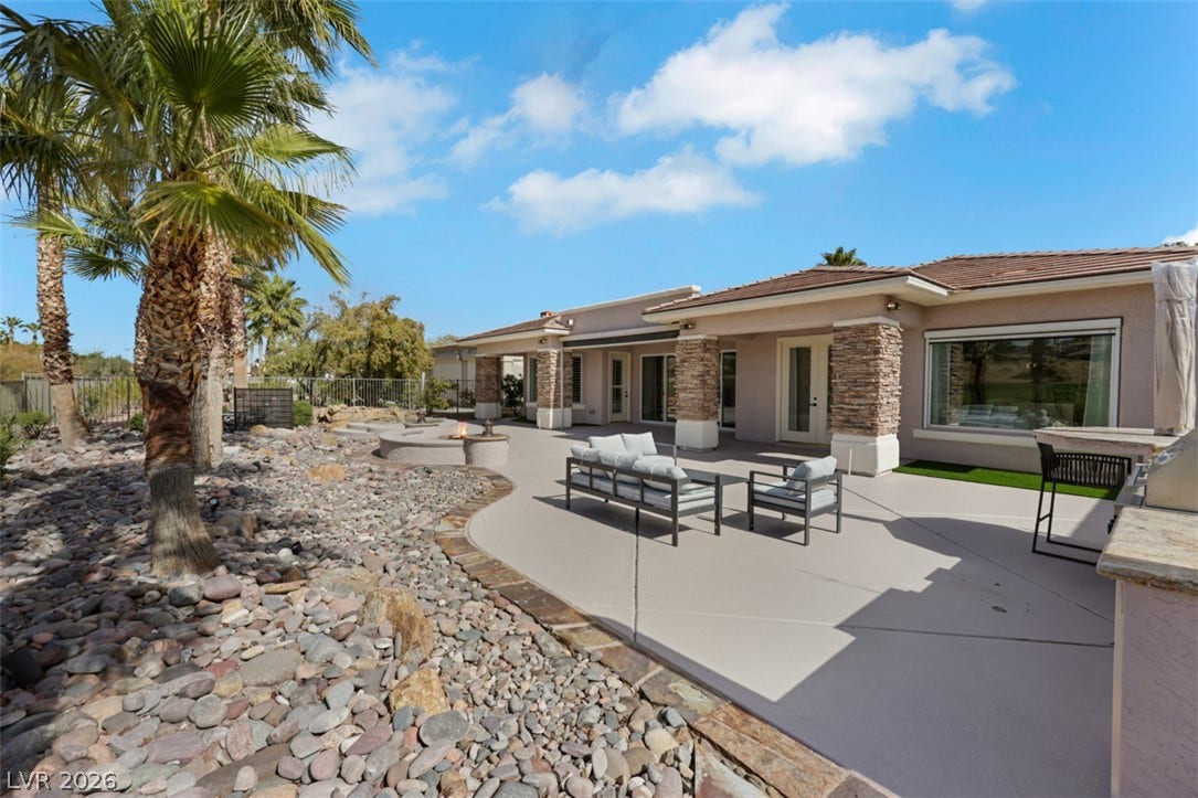 5015 Rivedro Street, Las Vegas, NV 89135 A spacious backyard patio lined with stone pillars opens onto a xeriscaped lawn under clear skies.