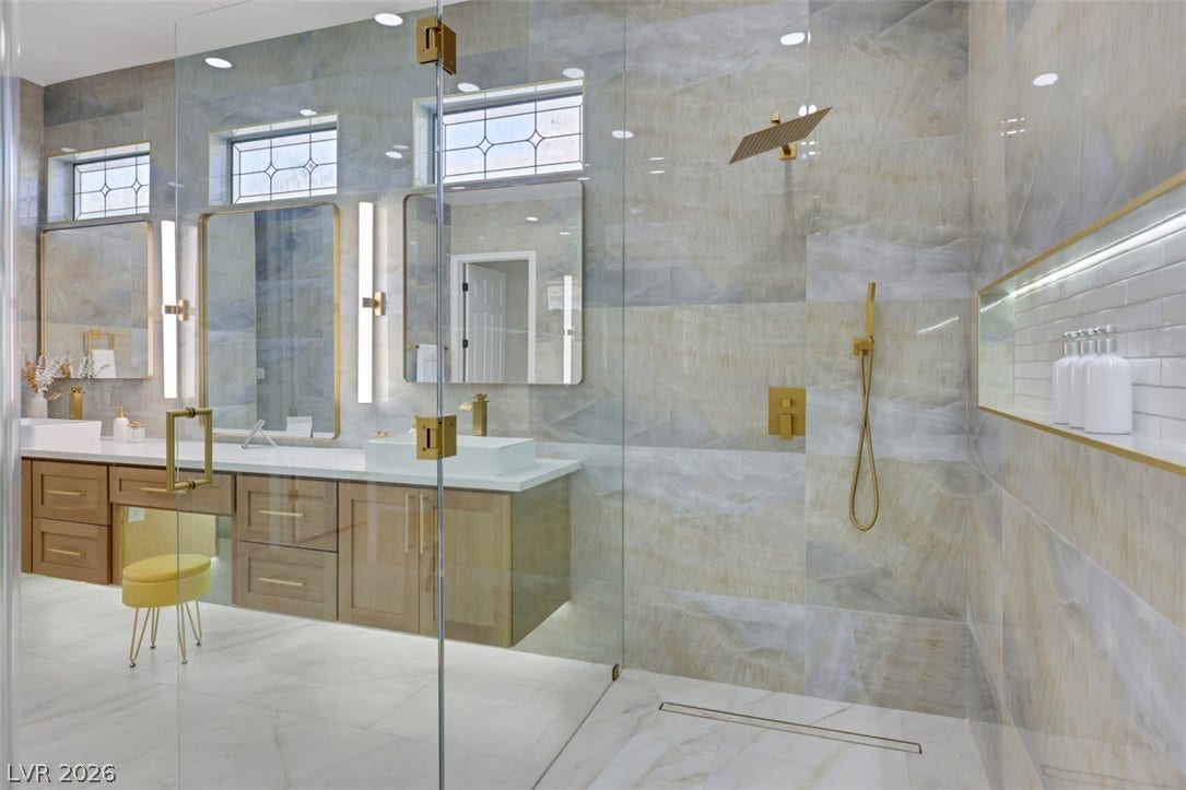 5015 Rivedro Street, Las Vegas, NV 89135 A spacious double vanity and a glass-enclosed shower showcase custom tilework and gold-tone fixtures.