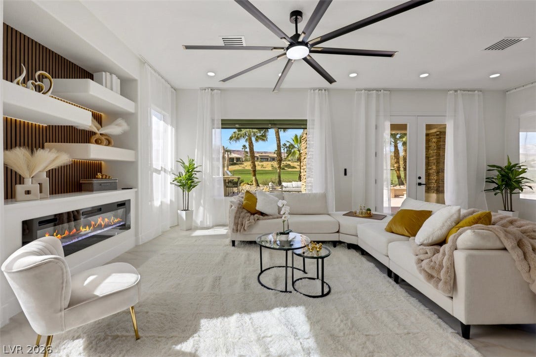 5015 Rivedro Street, Las Vegas, NV 89135 An elegant modern fireplace and custom open shelving anchor this bright, tile-floored living area.