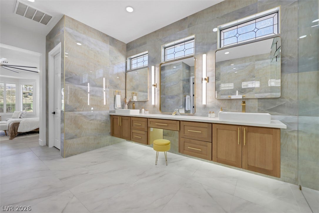 5015 Rivedro Street, Las Vegas, NV 89135 Floor-to-ceiling tilework and a floating double vanity elevate this primary bathroom design.