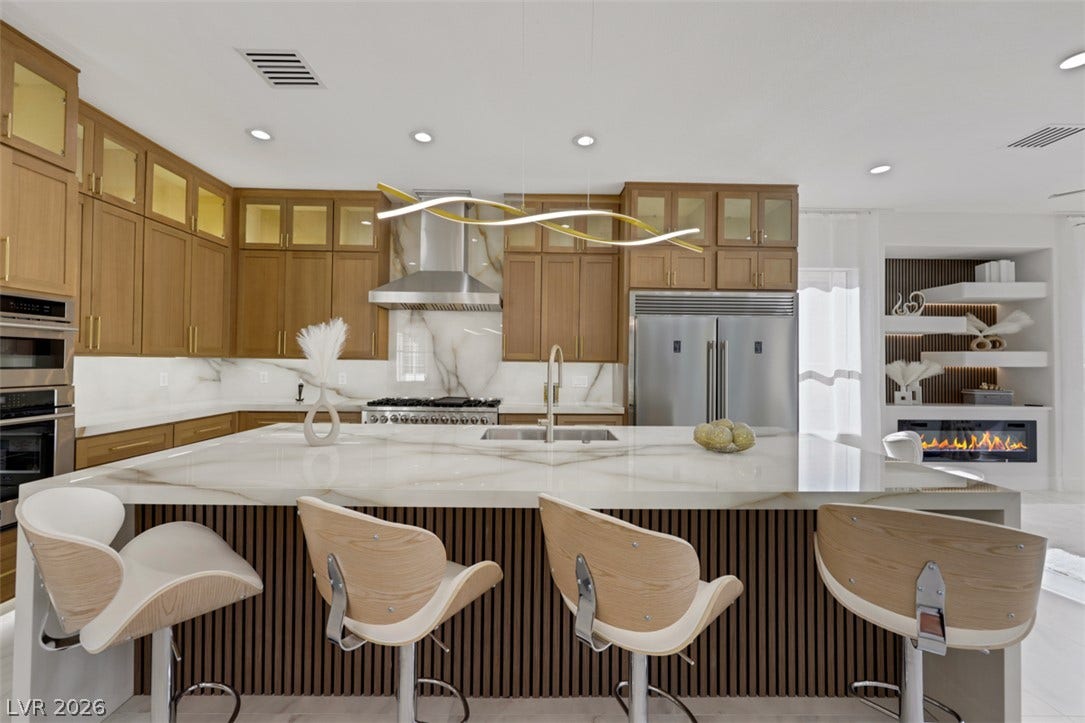 5015 Rivedro Street, Las Vegas, NV 89135 Gleaming stone countertops and warm wood cabinetry define this modern kitchen anchored by a large island.