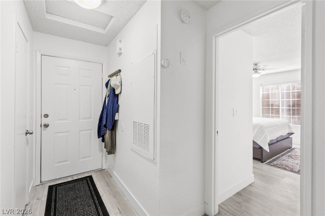 2200 S Fort Apache Road, #2156, Las Vegas, NV 89117 The front door opens to a welcoming entry with durable wood-look flooring leading to a bedroom with window blinds.
