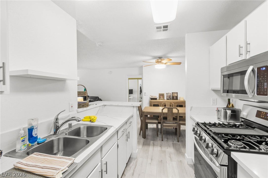 2200 S Fort Apache Road, #2156, Las Vegas, NV 89117 A well-lit kitchen with sleek white cabinetry and modern stainless steel appliances.