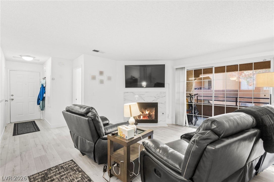 2200 S Fort Apache Road, #2156, Las Vegas, NV 89117 A welcoming living room features a cozy fireplace and convenient sliding glass doors leading to a balcony.