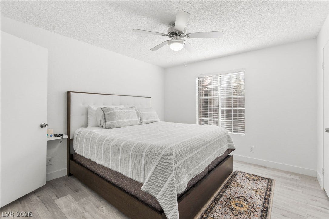 2200 S Fort Apache Road, #2156, Las Vegas, NV 89117 Relaxation awaits in this naturally illuminated bedroom featuring a classic ceiling fan and light wood-look flooring.
