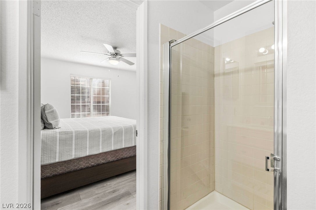 2200 S Fort Apache Road, #2156, Las Vegas, NV 89117 A well-appointed shower stall with clean tile work and clear glass entry, adjacent to a cozy bedroom.