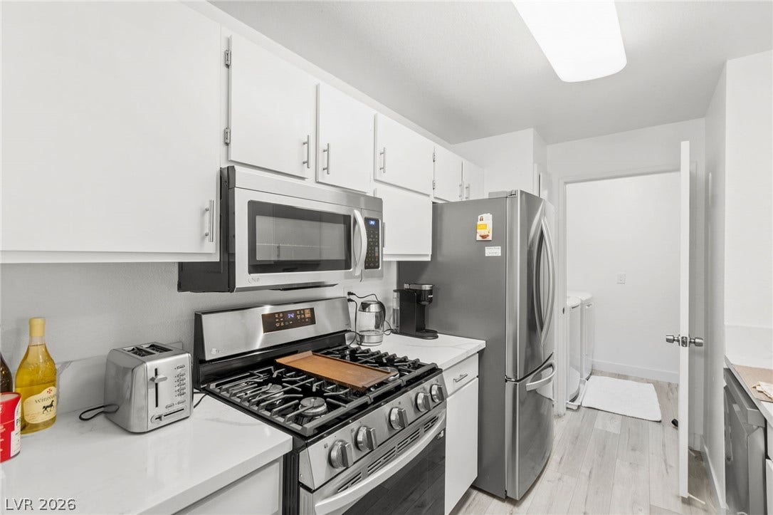2200 S Fort Apache Road, #2156, Las Vegas, NV 89117 A compact kitchen with sleek stainless steel appliances and abundant white cabinetry.