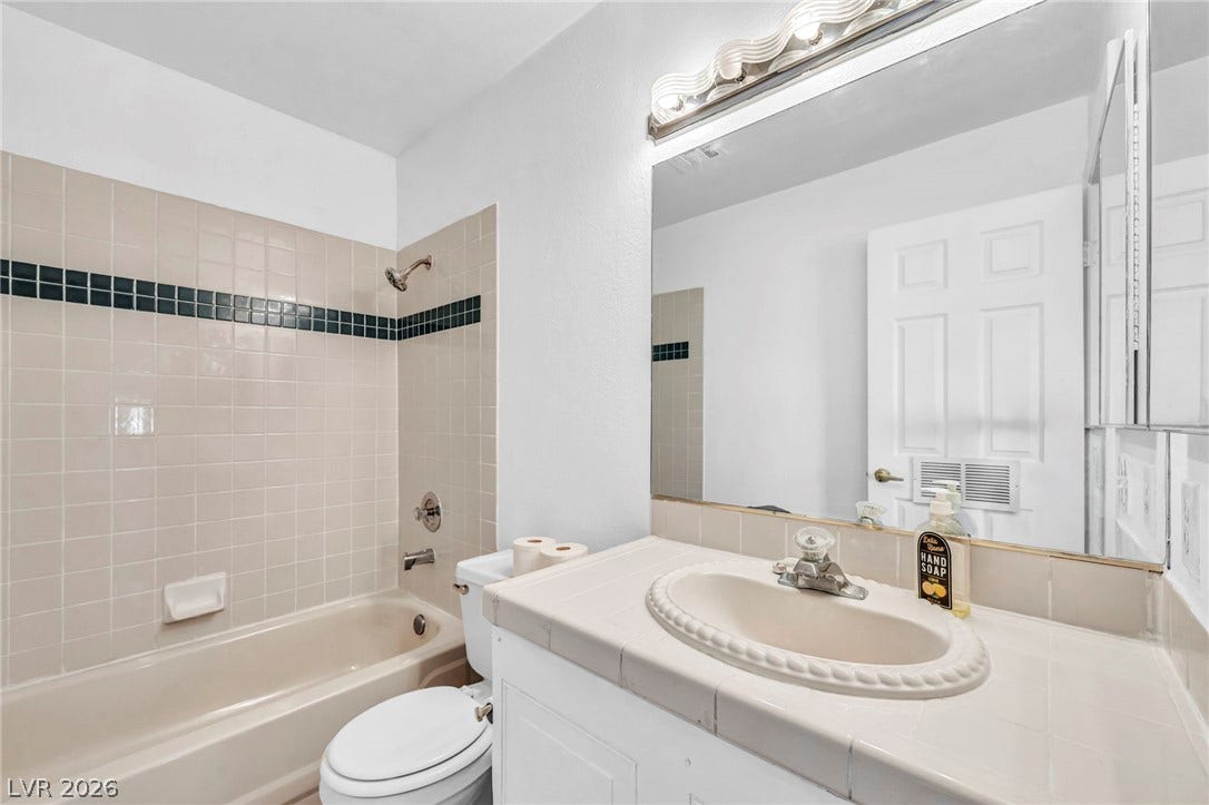 Classic tile countertops and a matching tub surround define this functional bathroom space.
