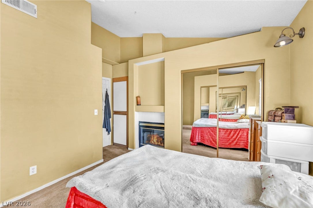 High vaulted ceilings and a cozy fireplace create a comfortable atmosphere in this spacious bedroom.
