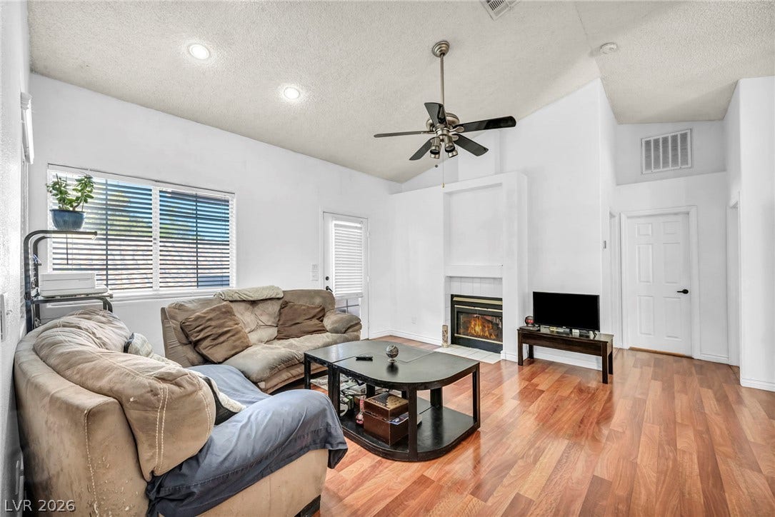 Gleaming hardwood floors and a warm fireplace define this vaulted living room space.