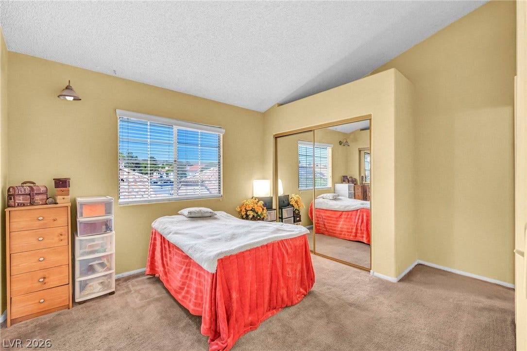 Vaulted ceilings and mirrored closet doors enhance this carpeted bedroom.