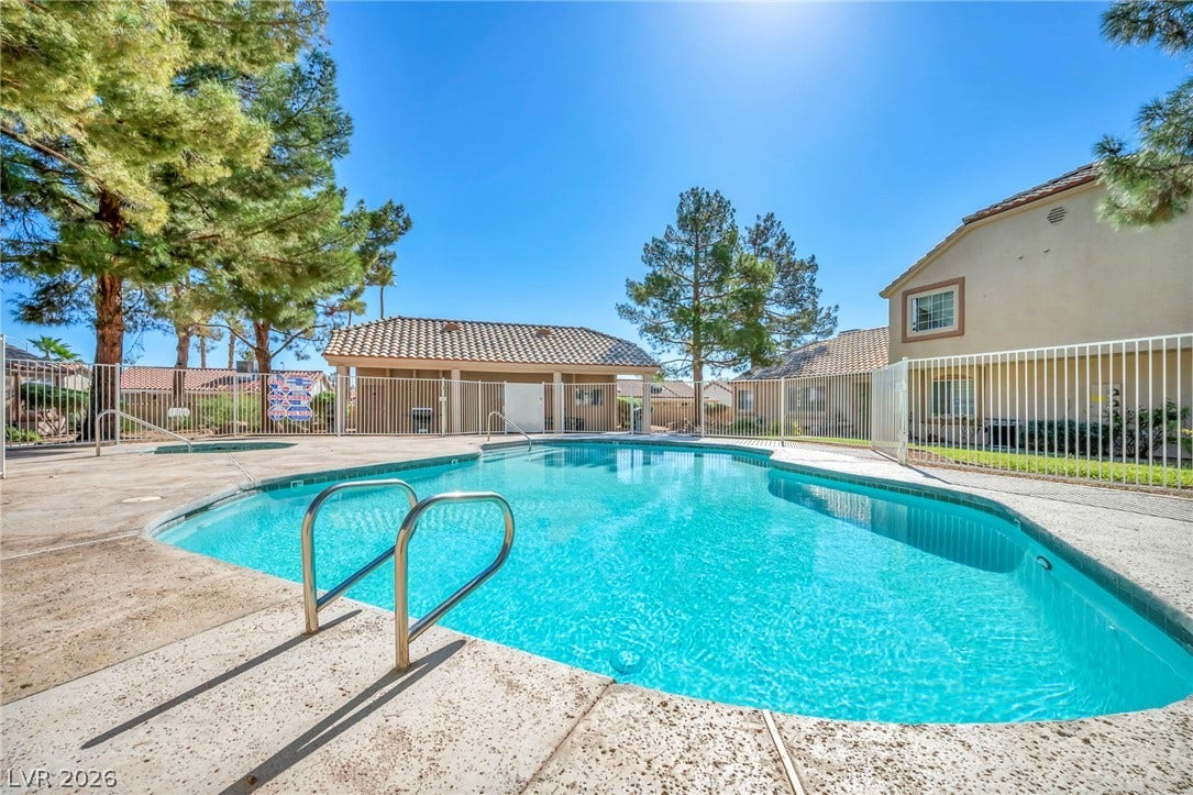 Mature pines and a security fence surround the sparkling community swimming pool.