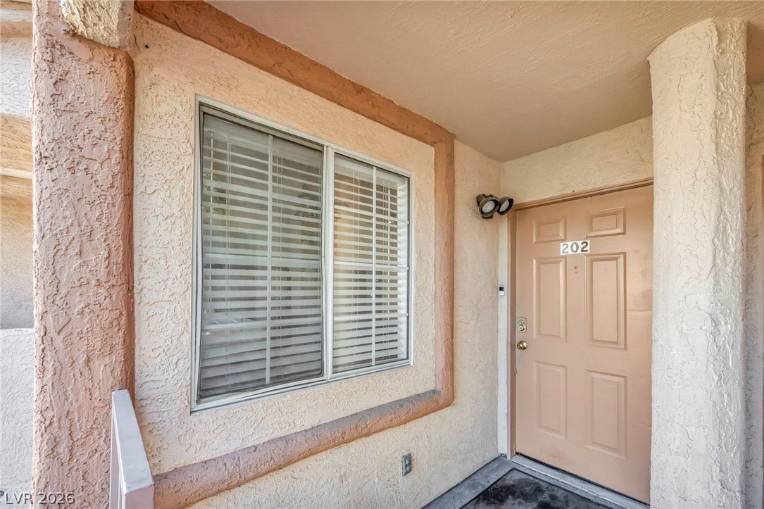 Textured stucco pillars frame this inviting entryway with its classic six-panel door.