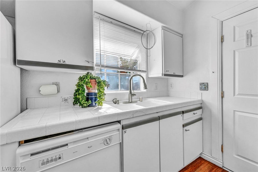 Tiled countertops and rich wood flooring anchor this functional kitchen workspace.