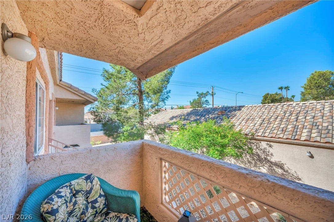 An elevated perspective overlooks the surrounding neighborhood from a stucco-finished balcony with tile roof views.