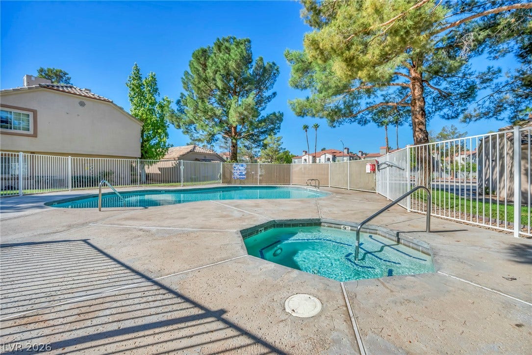 A fenced concrete patio surrounds a refreshing community pool and an in-ground spa.