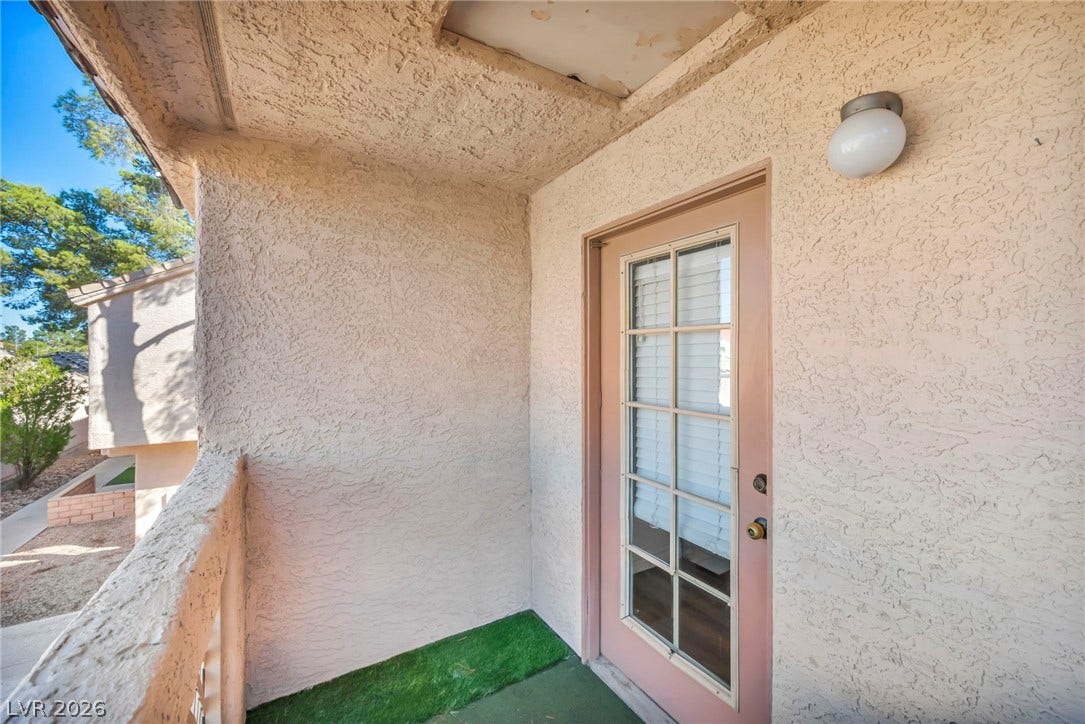 Textured stucco walls enclose a private balcony featuring a classic multi-lite glass door.