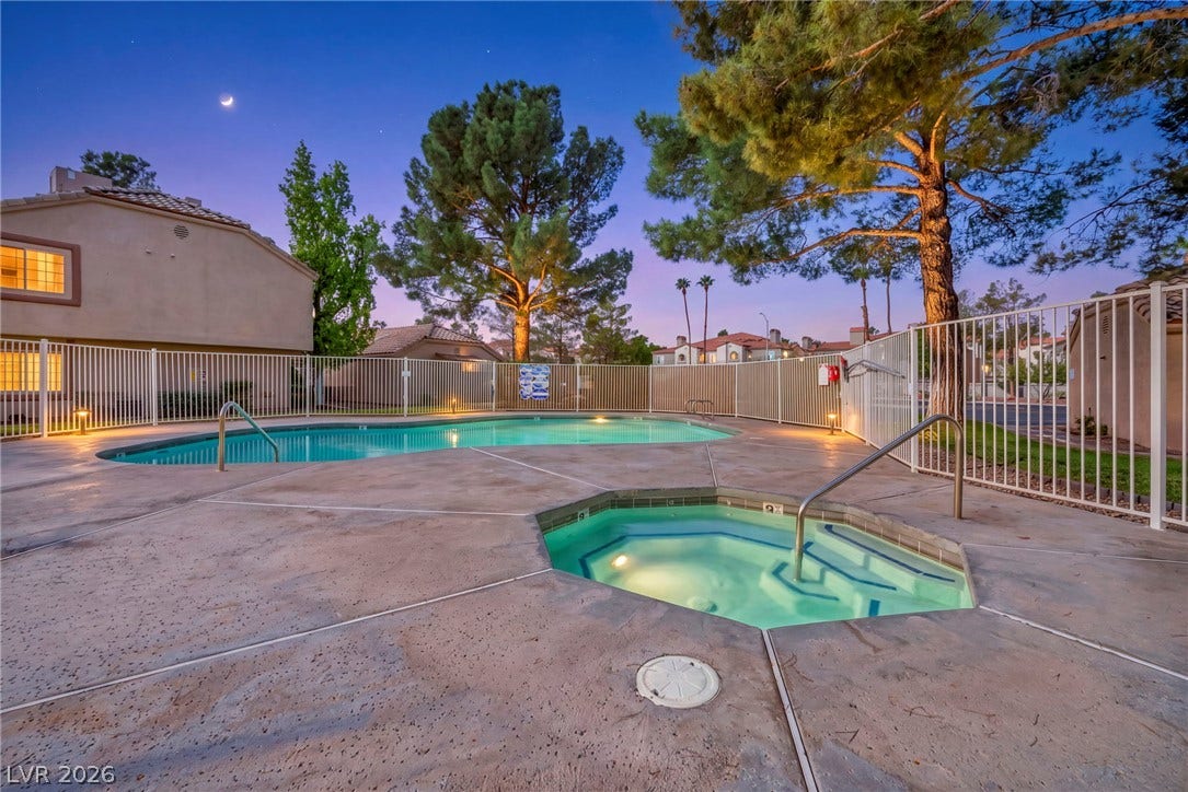 An inviting pool and spa area sits enclosed by secure fencing beneath mature shade trees.