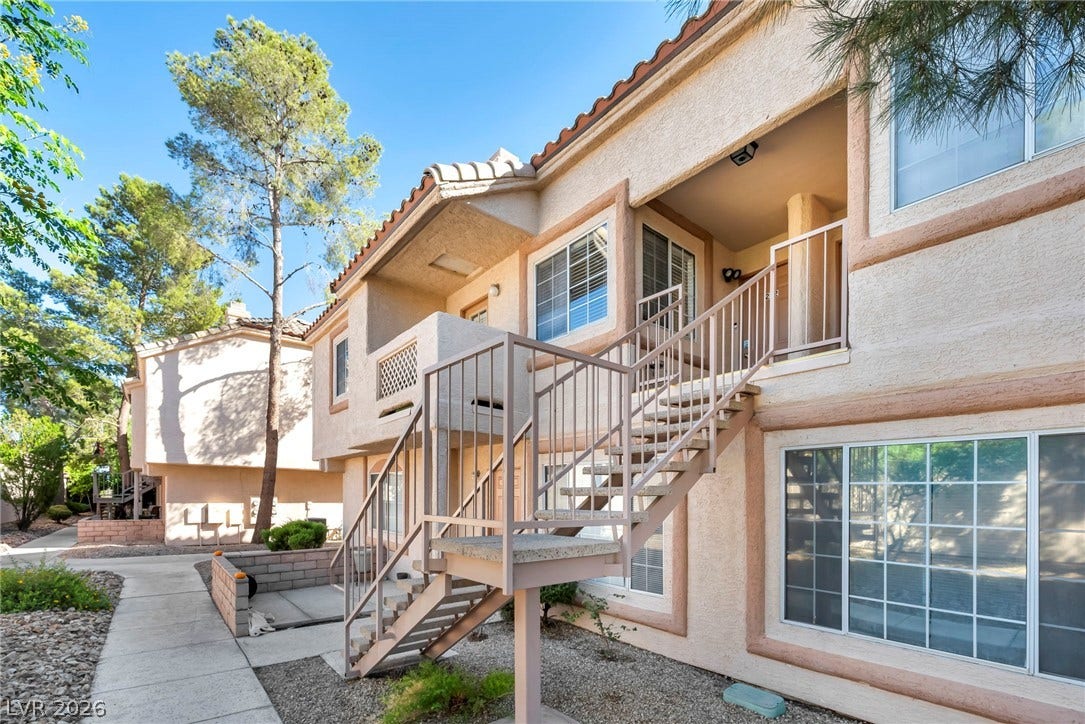 Multi-level residential architecture features stucco siding under a classic spanish tile roof.
