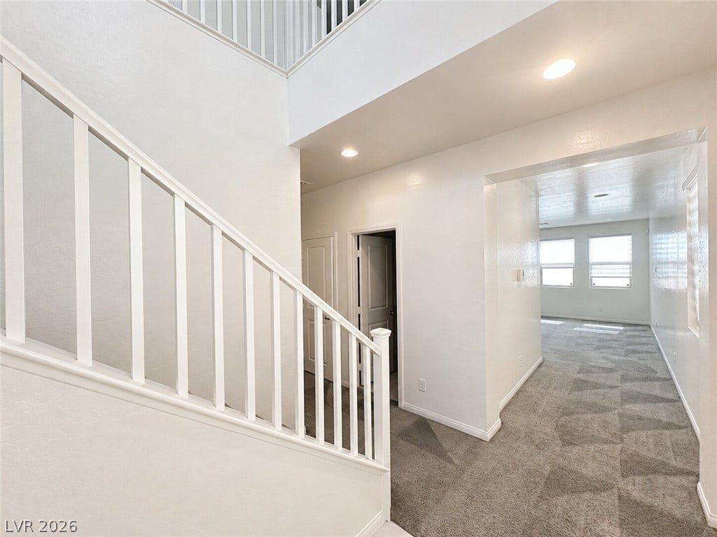 An inviting entryway transitions seamlessly into an open-concept living area with plush carpeting.