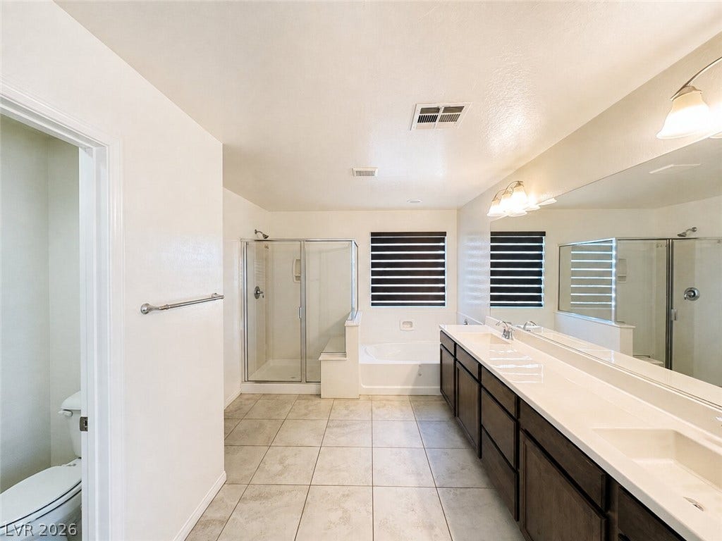 A long double vanity and large tile flooring define this spacious bathroom.