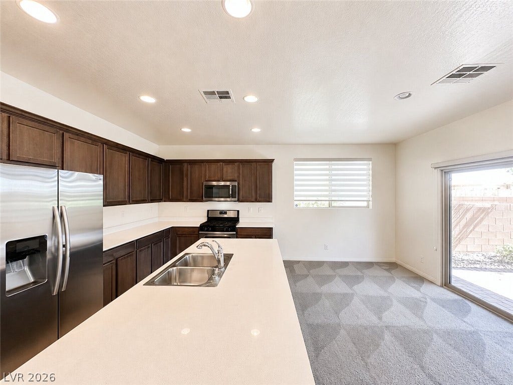 Rich wood cabinetry contrasts beautifully with pristine solid-surface countertops in this open culinary space.