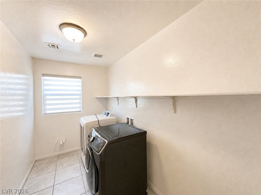 Functional tile flooring and long open shelving define this practical dedicated laundry space.