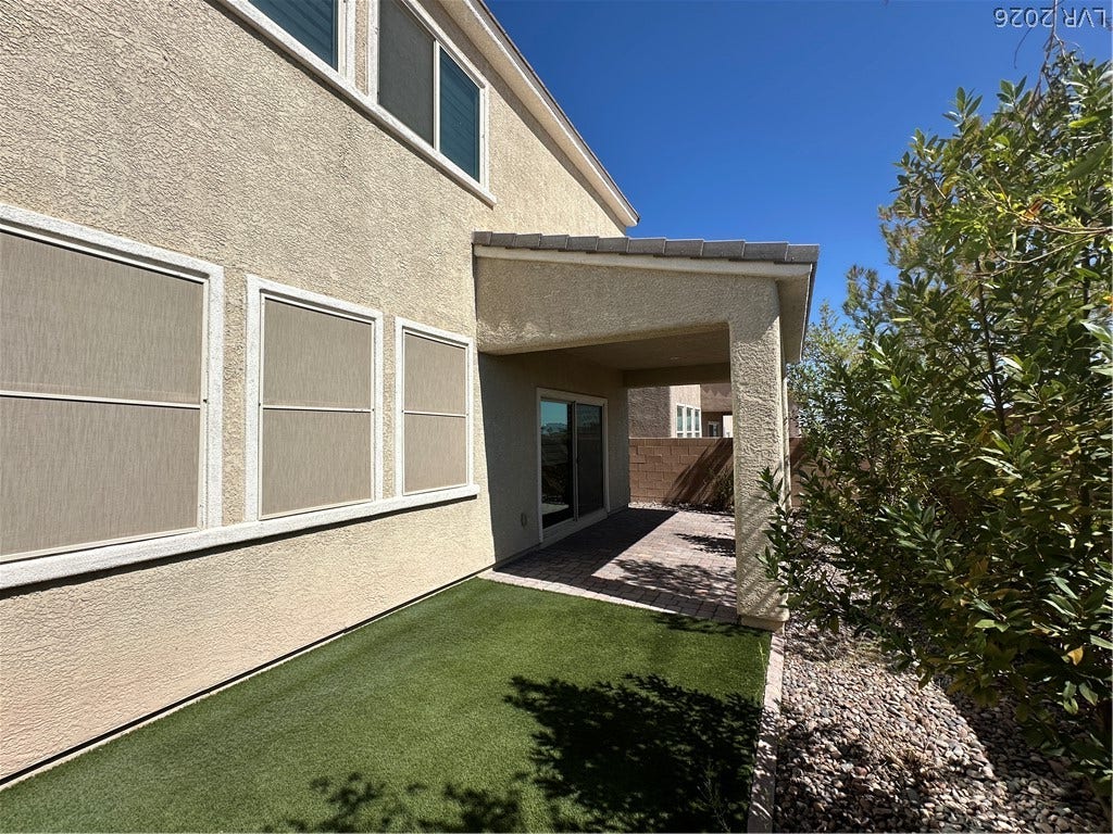 Stucco exterior finishes stand out alongside a covered patio and a manicured lawn.