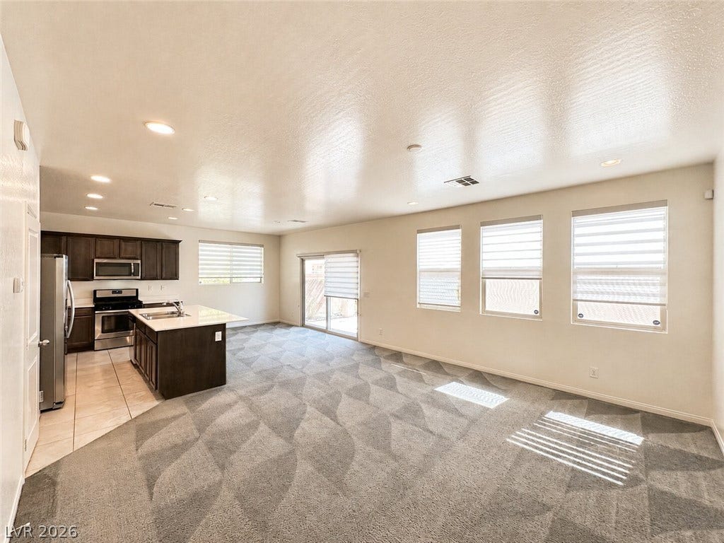 An open layout connects the carpeted living space directly to the kitchen.