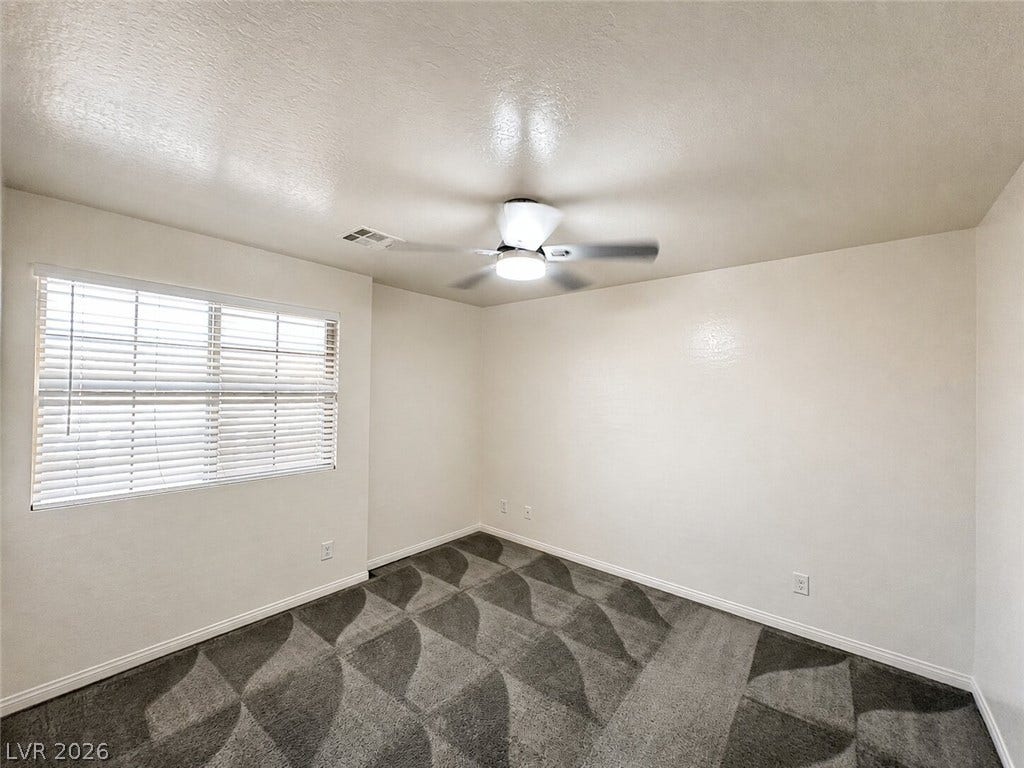 Patterned carpeting and a wide window create a cozy retreat in this classic room.