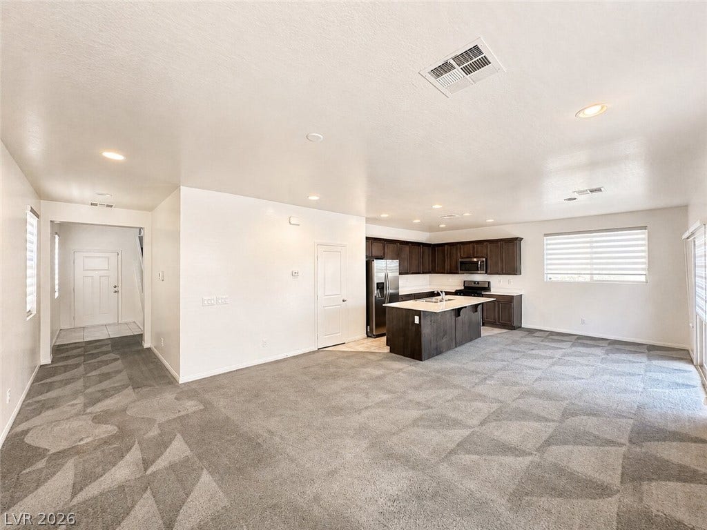 An open floor plan seamlessly connects a carpeted living area to the kitchen.